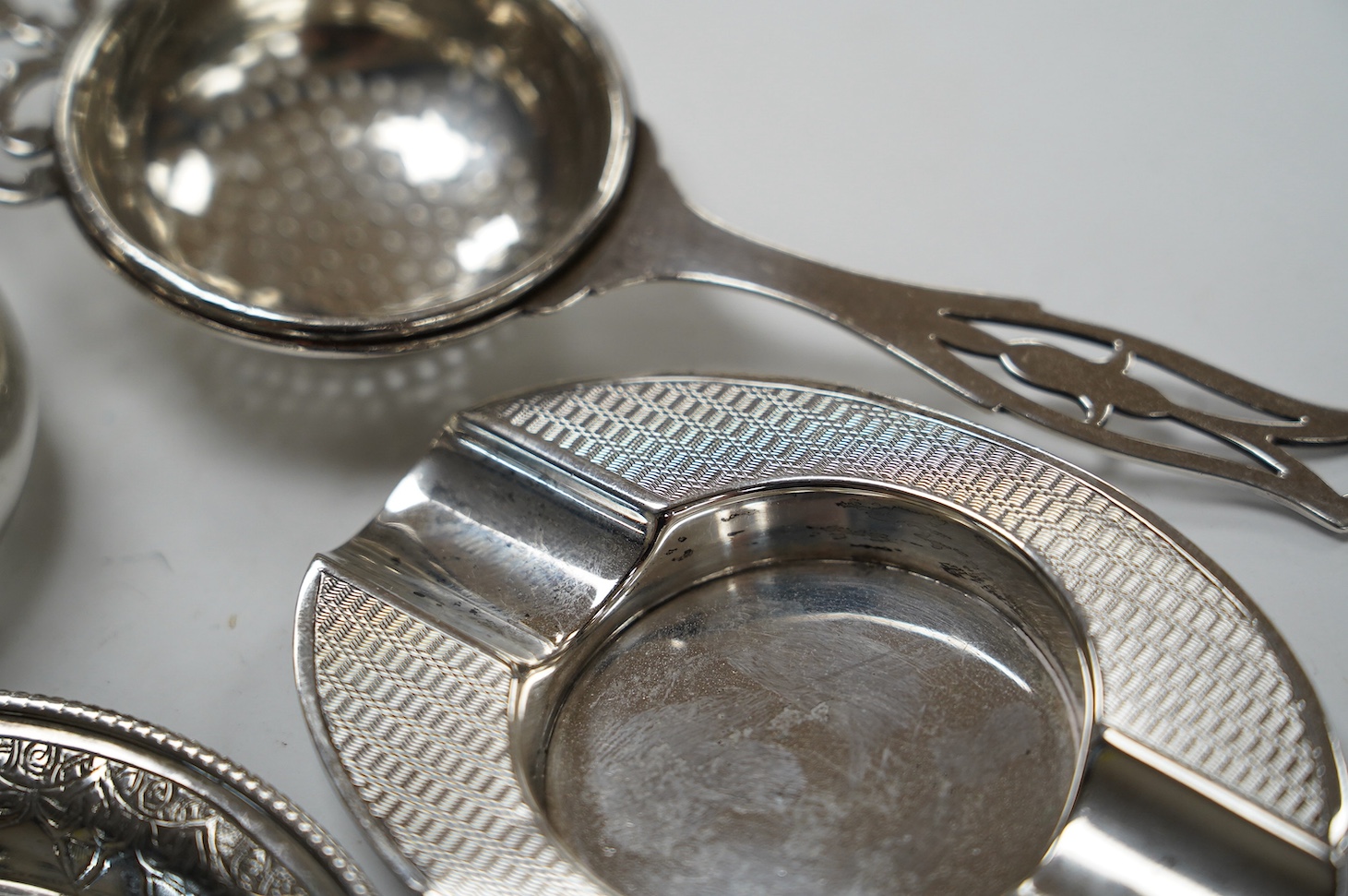 Sundry small silver and white metal items including silver tea strainer on stand and ashtray, pierced silver bowl, sterling dishes and dwarf candlesticks, etc. Condition - poor to fair